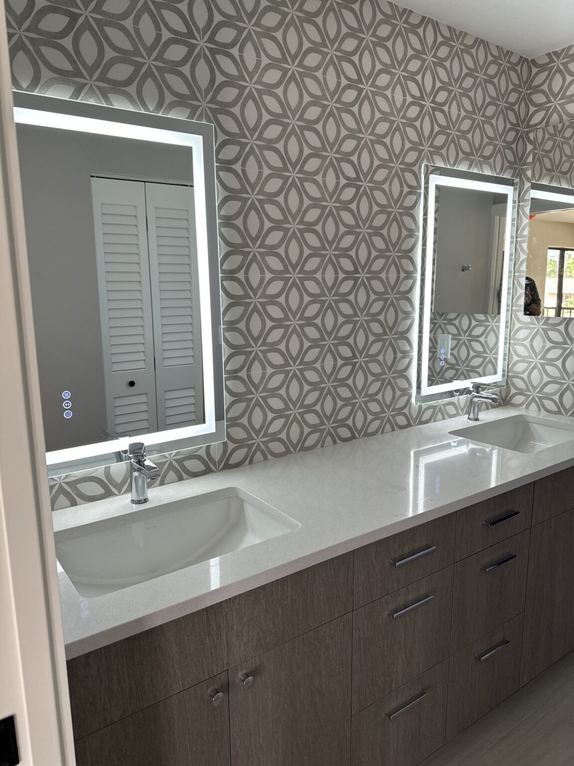 Remodeled bathroom with a double vanity and lighted mirrors