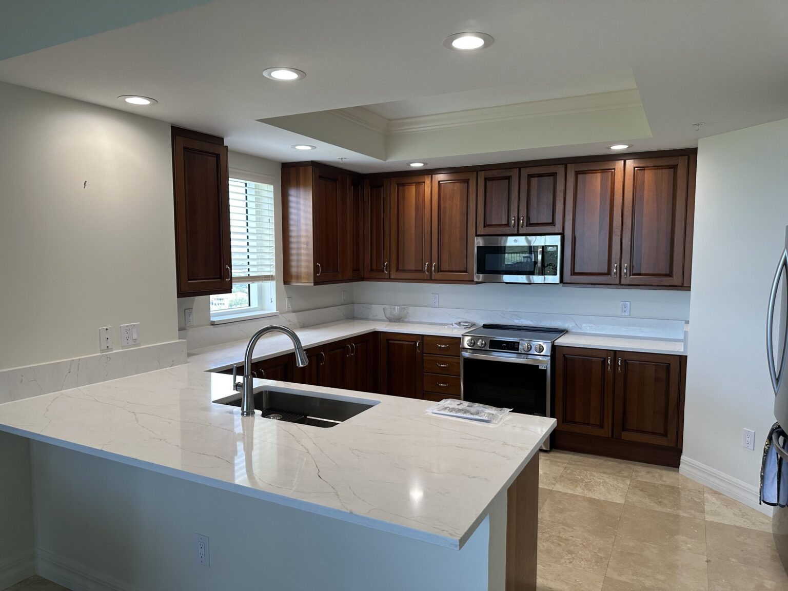 Remodeled kitchen with dark wood cabinetry and white quartz countertops