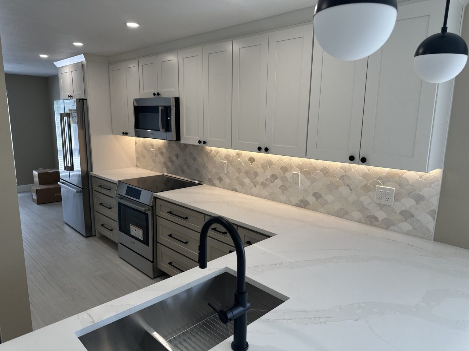 Remodeled kitchen with a quartz waterfall island and pendant lighting
